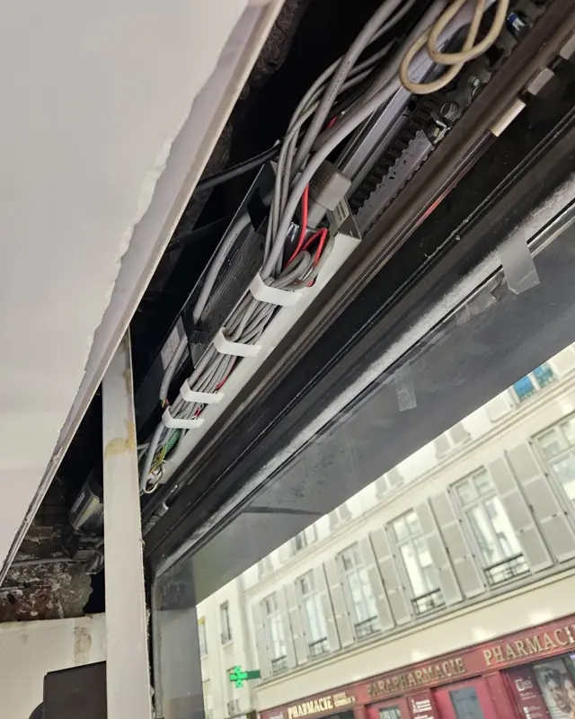 Mécanisme d'une porte automatique de magasin, rue parisienne en arrière-plan